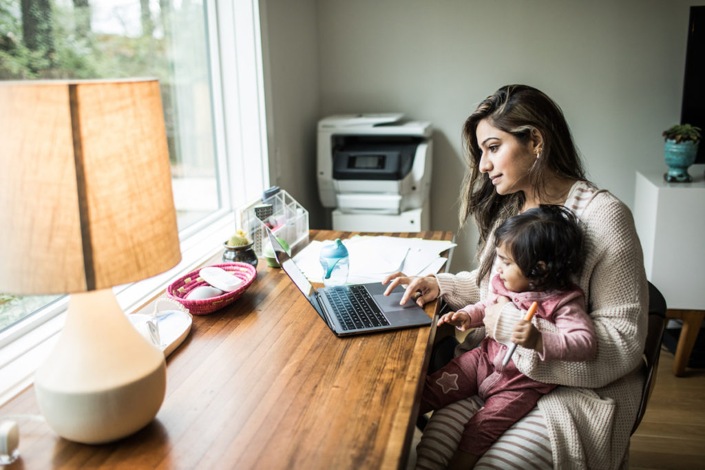 Mother multi-tasking with infant daughter in home office