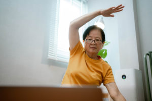 Asian senior woman watching video workout and training at home.