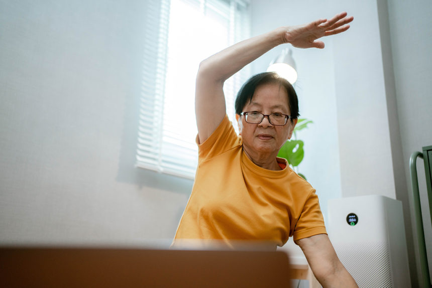 Asian senior woman watching video workout and training at home.