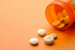 White color medical pills spilling on orange background,Romania
