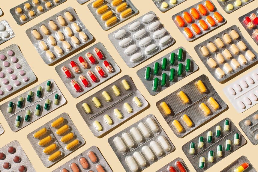Blisters with colorful pills and capsules on beige background. Minimal medical, health care, pharmacology concept.
